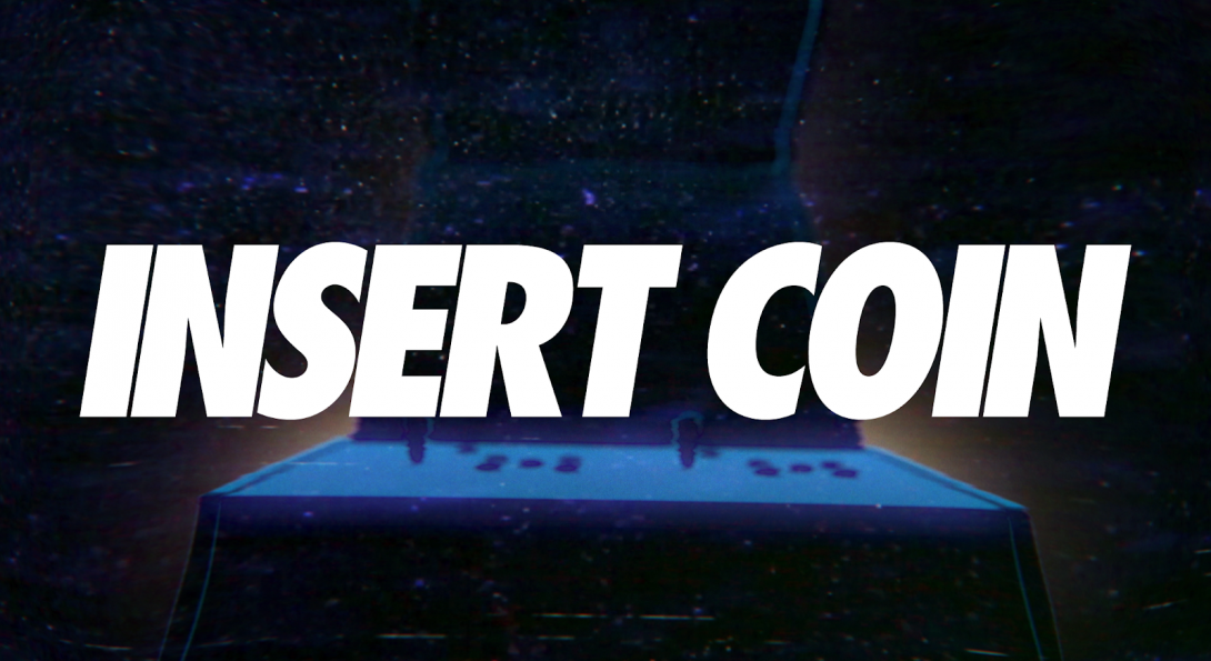 A created image with the words “Insert Coin” in bold, white, large letters. Behind the text is a dark blue image of a game machine and a dark blue background.