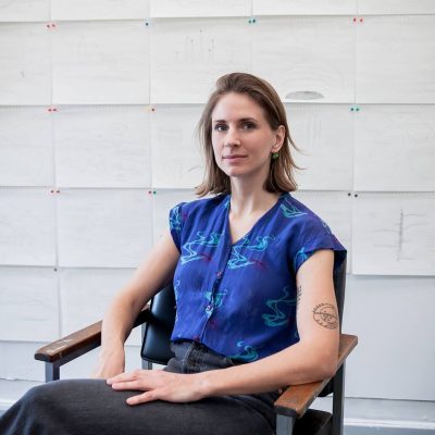 White woman with brown hair seated in a chair.