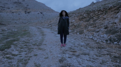 Woman standing in a rocky landscape.